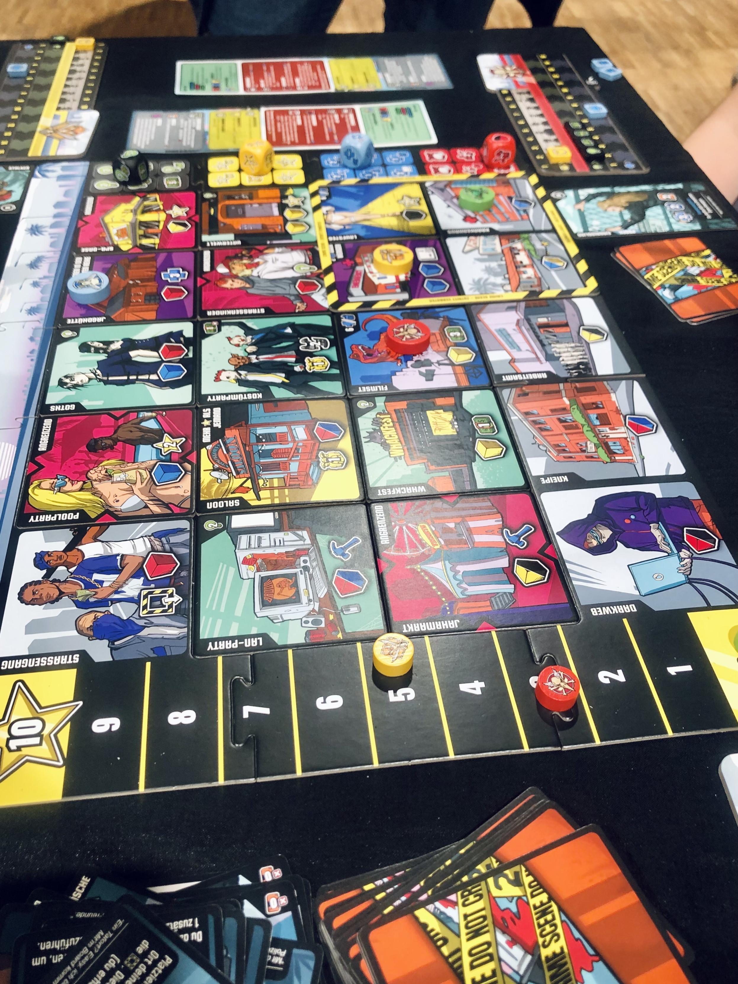 Whacktown, Ansicht von oben auf den Spielplan der Gangster Stadt Whacktown. Quadratische Blättchen die ein Raster von 4*5 Feldern die Stadt bilden. Jeder Ort (Plättchen) hat eigene Aktionen die bei betretten aktiviert werden. Davon sind 15 Orte austauschbar und ergeben modular immer ein anderes Stadtbild. Etwa 80 weitere Orte sollen im Spiel noch vorkommen. Material sind Holzscheiben, große Würfel, Handkarten und ein eigenes Tableau um Stärke und Lebenspunkte zu zählen.