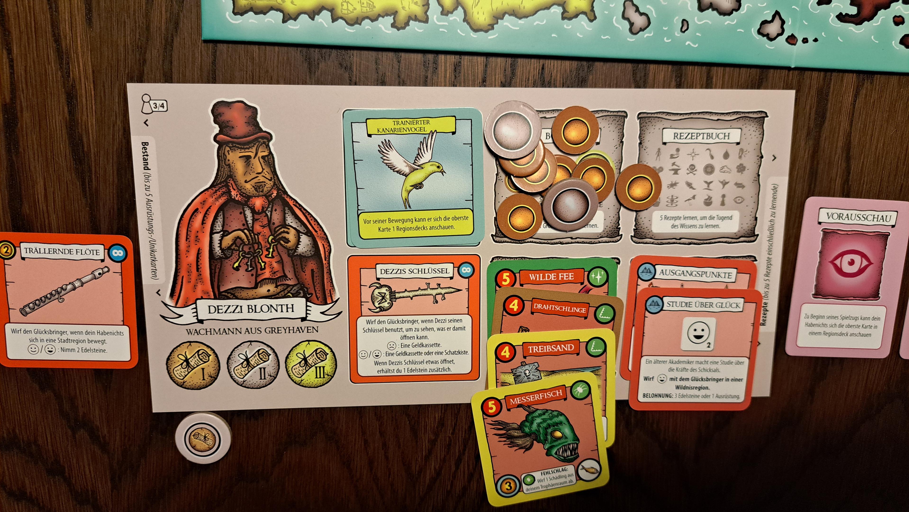 My character's board. The character is a guard from Greyhaven with brown skin and a thin, curvy moustache. He wears a red hat and a red cape and holds keys. On the board are various cards, including a bird card (trained canary), my character's special item (keys), some diamond tokens, a collection of battle trophy cards, a list of all possible recipe symbols, and 2 quest cards. Next to the board is an item card (a flute), and a recipe card (foresight).